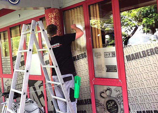Ein Mitarbeiter von Baden Dienstleistungen reinigt die Fenster eines Geschäftes